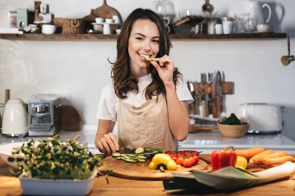 Gyönyörű fiatal nő visel kötényt főzés zöldségek — Stock Fotó