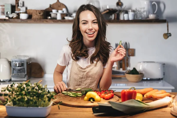 Hermosa mujer joven con delantal cocinar verduras —  Fotos de Stock