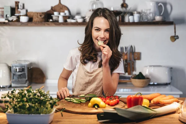 Güzel genç kadın apron pişirme sebze giyiyor — Stok fotoğraf