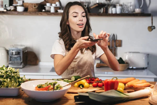 Vacker ung kvinna klädd förkläde matlagning grönsaker — Stockfoto