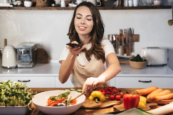 Gyönyörű fiatal nő visel kötényt főzés zöldségek — Stock Fotó