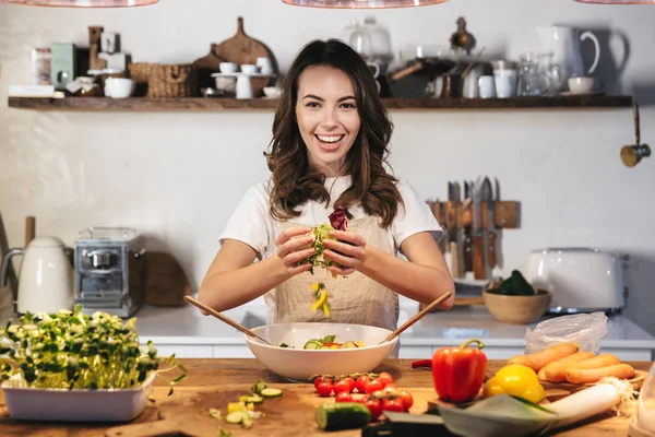 Güzel genç kadın apron pişirme sebze giyiyor — Stok fotoğraf