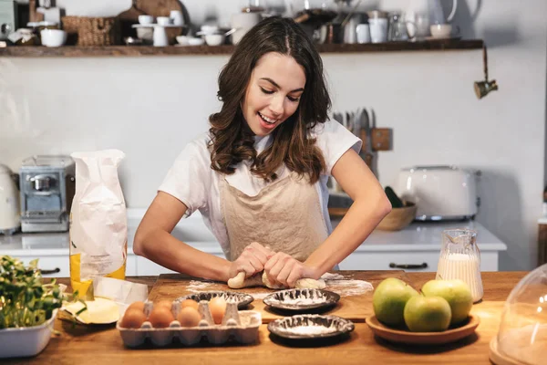 Joyeux jeune femme portant tablier préparant la pâte — Photo