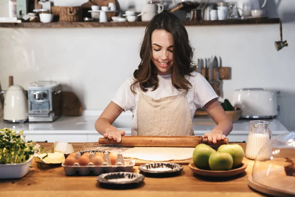 Allegro giovane donna che indossa grembiule preparazione pasta — Foto Stock