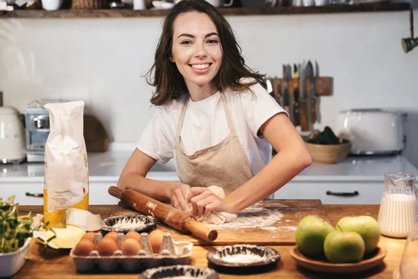 Allegro giovane donna che indossa grembiule preparazione pasta — Foto Stock