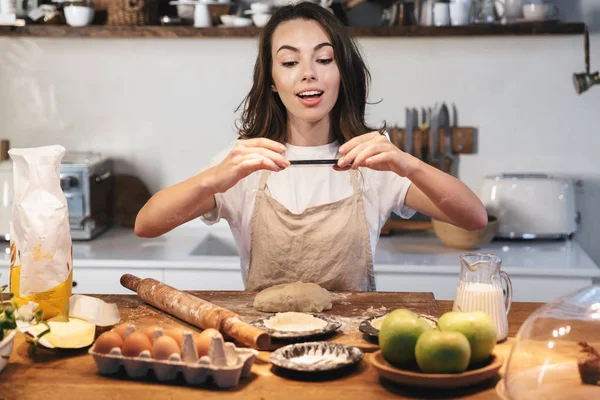 Joyeux jeune femme portant tablier préparant la pâte — Photo