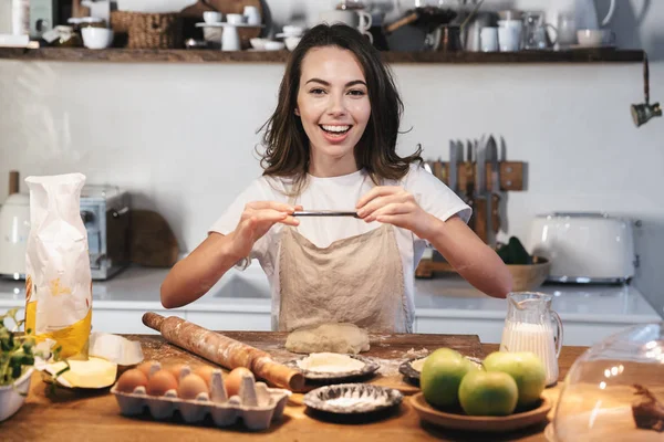 Hamur hazırlayan önlük giyen neşeli genç kadın