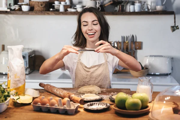 Joyeux jeune femme portant tablier préparant la pâte — Photo