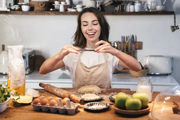 Allegro giovane donna che indossa grembiule preparazione pasta — Foto Stock