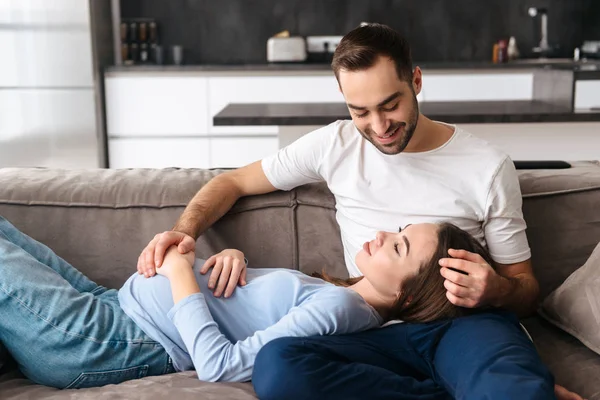 Lycklig ung gravid par koppla av på en soffa — Stockfoto