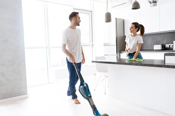 Feliz jovem casal fazendo geral limpo na cozinha — Fotografia de Stock
