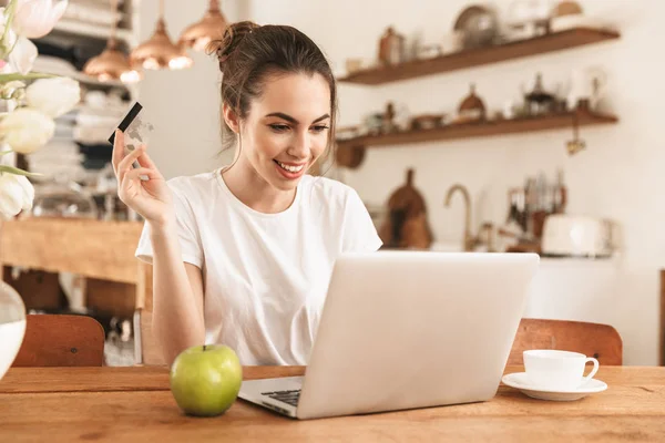 Belle jeune fille étudiante avec pomme à l'intérieur en utilisant un ordinateur portable tenant la carte de crédit . — Photo