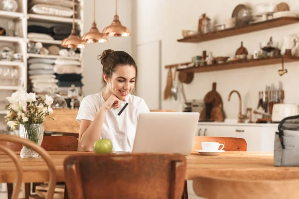 Vacker ung student tjej med äpple inomhus med bärbar dator som innehar kreditkort. — Stockfoto