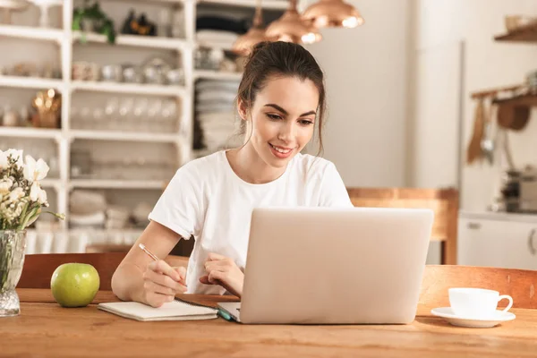 Schöne junge Studentin mit Apfel drinnen mit Laptop-Computer. — Stockfoto