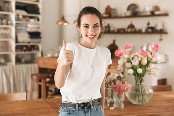 Belle jeune étudiante en t-shirt blanc à l'intérieur posant montrant les pouces geste . — Photo