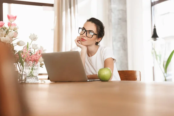 Beautiful young student girl sitting indoors using laptop computer. — Stock Photo, Image