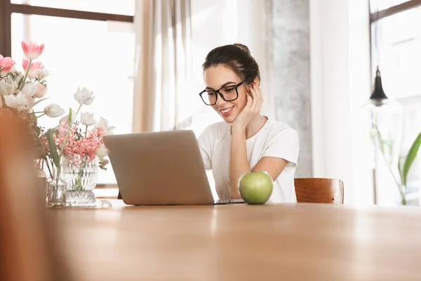 Schöne junge Studentin sitzt drinnen mit Laptop-Computer. — Stockfoto