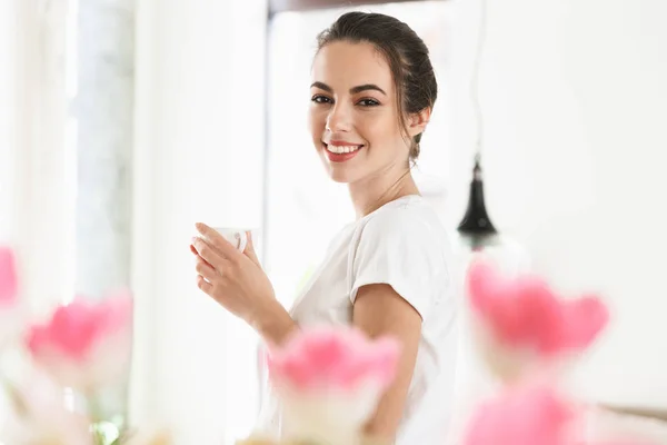 Menina estudante bonita bebendo café posando dentro de casa . — Fotografia de Stock