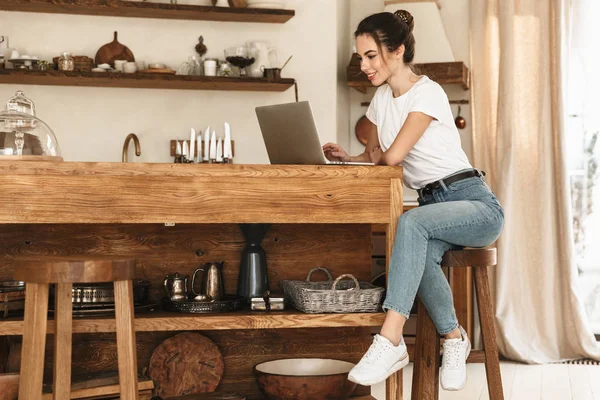 Vacker ung student tjej sitter inomhus med bärbar dator. — Stockfoto