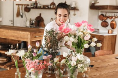 Mutlu genç öğrenci kız çiçeklerin yakınında kapalı poz.