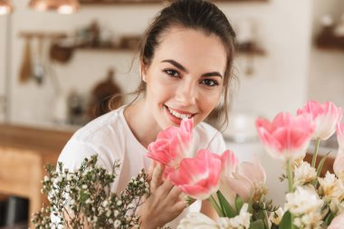 Mutlu genç öğrenci kız çiçeklerin yakınında kapalı poz.
