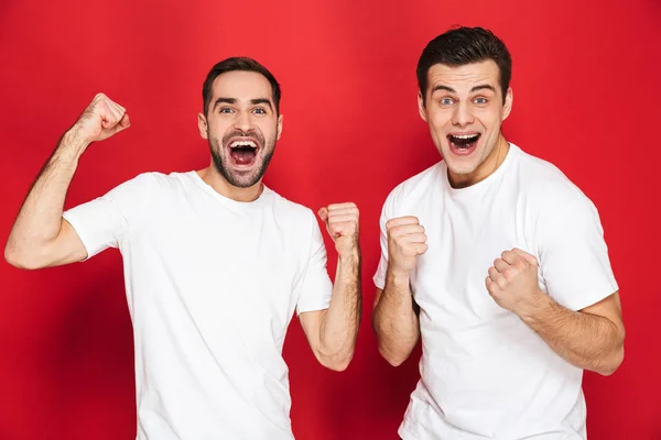 Изображение двух веселых мужчин, 30-летних друзей в белых футболках, радующихся — стоковое фото