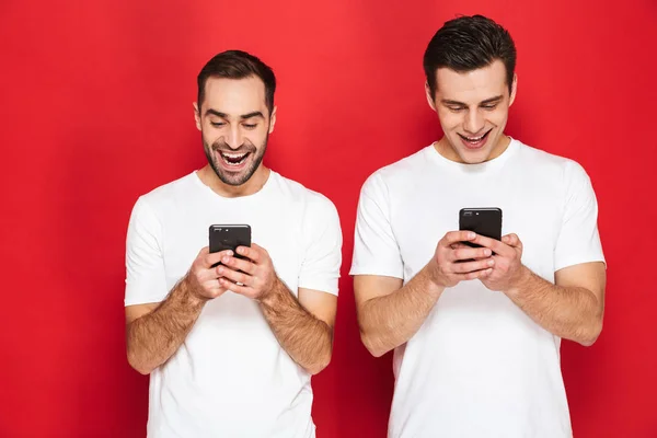 Image of two attractive men friends 30s in white t-shirts smilin