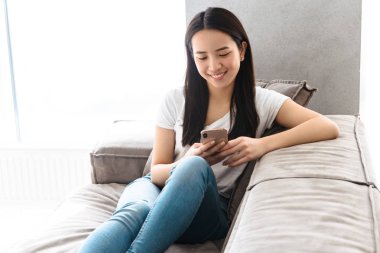 Bu yüzden otururken akıllı telefon kullanarak rahat asyalı kız Görüntü