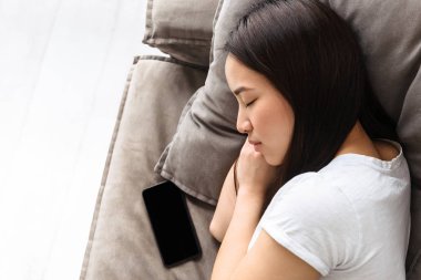 Smartp ile kanepede yatan ve uyuyan genç asyalı kız görüntüsü