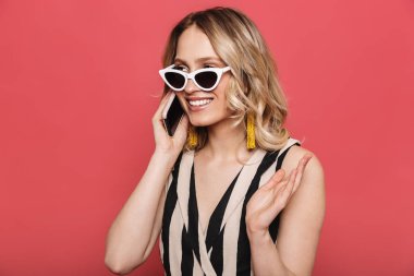 İnanılmaz genç kadın cep telefonu ile konuşurken kırmızı mercan arka plan üzerinde izole poz.