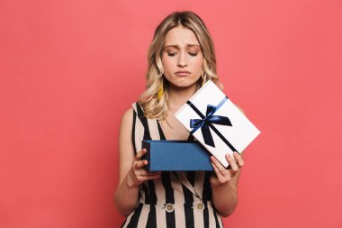 Güzel hoşnutsuz genç kadın mevcut kutu tutan kırmızı mercan arka plan üzerinde izole poz.