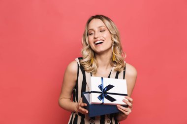 Mutlu genç kadın mevcut kutu tutan kırmızı mercan arka plan üzerinde izole poz.