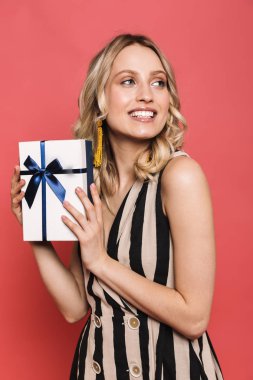 Mutlu genç kadın mevcut kutu tutan kırmızı mercan arka plan üzerinde izole poz.