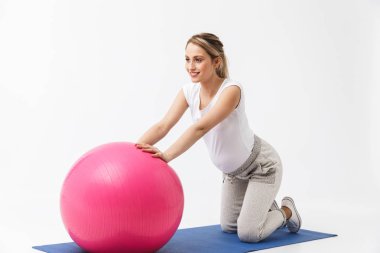 Güzel genç hamile yoga fitness kadın beyaz duvar arka plan üzerinde izole poz topu ile egzersizyapmak.