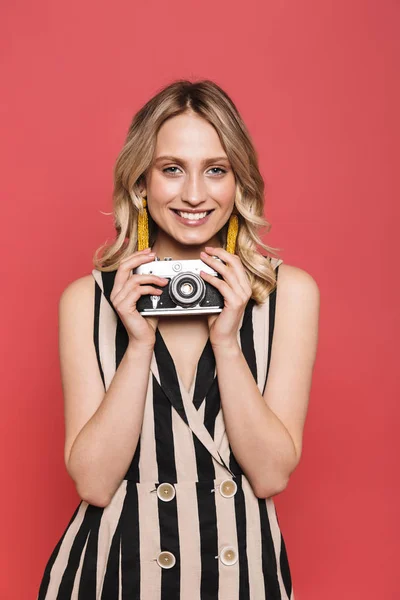 Bella sorprendente giovane donna fotografo turistico posa isolato su sfondo di corallo rosso tenendo la fotocamera . — Foto Stock