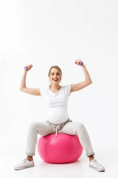 Όμορφη νεαρή έγκυος γιόγκα Fitness γυναίκα που παρουσιάζουν απομονωμένα πάνω λευκό τοίχο φόντο κάνει ασκήσεις με μπάλα. — Φωτογραφία Αρχείου