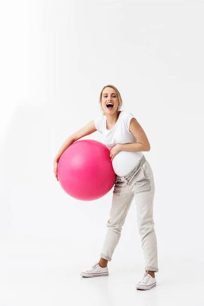 Hermosa joven embarazada yoga fitness mujer posando aislado sobre fondo de pared blanca hacer ejercicios con pelota . — Foto de Stock