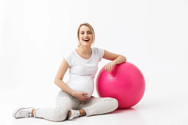 Hermosa joven embarazada yoga fitness mujer posando aislado sobre fondo de pared blanca hacer ejercicios con pelota . —  Fotos de Stock