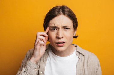 Gömlekli genç adam kameraya bakıyor.