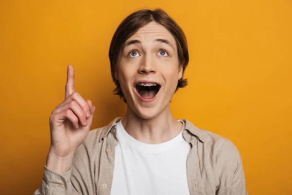 Homem bonito alegre na camisa apontando e olhando para cima — Fotografia de Stock