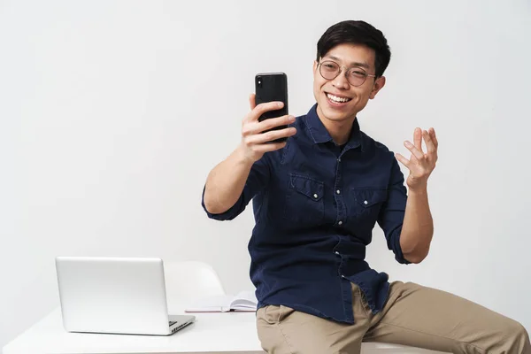 Foto de un alegre hombre de negocios asiático sentado a la mesa y sosteniendo —  Fotos de Stock