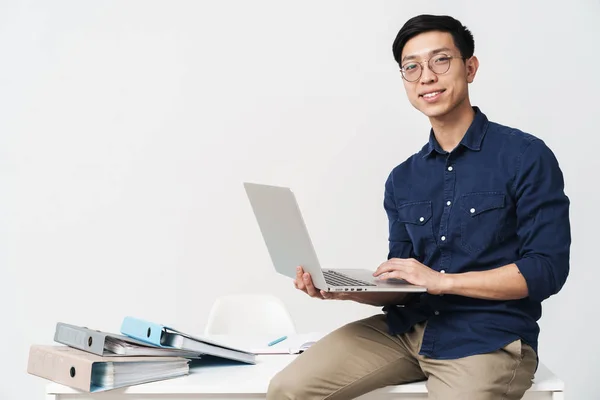 Foto di sorridente uomo asiatico 20s indossare occhiali seduto al tab — Foto Stock