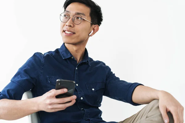 Foto do empresário chinês alegre 20s usando fones de ouvido sentado — Fotografia de Stock