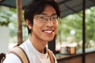 Sırt çantası giyen gülümseyen Asyalı öğrenci adam