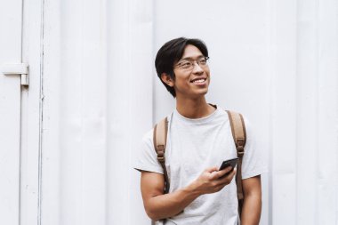 Sırt çantası taşıyan gülümseyen genç Asyalı adam öğrenci