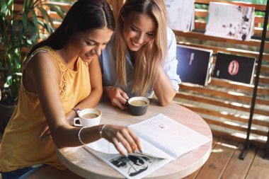 İki neşeli genç kız kapalı kafede oturan