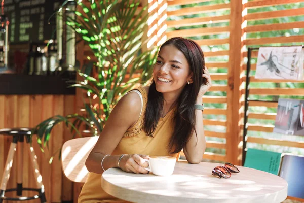 Усміхнена молода жінка сидить у кафе — стокове фото