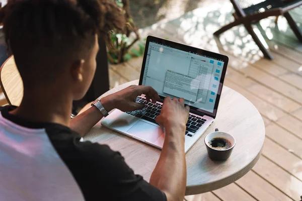 Vista posteriore di un giovane uomo africano che utilizza il computer portatile — Foto Stock