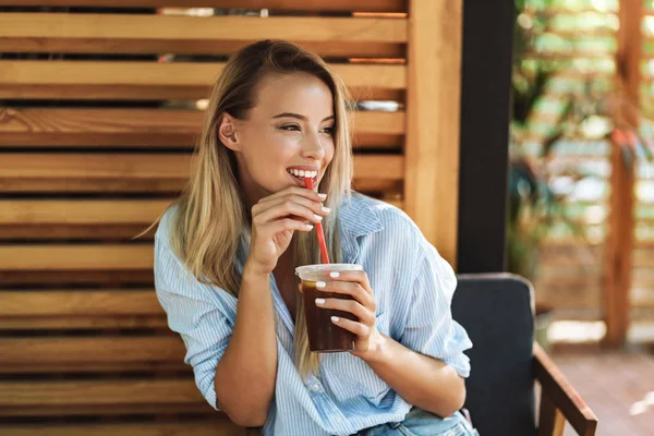 Lachende jonge vrouw drinken sap terwijl zittend in het café — Stockfoto