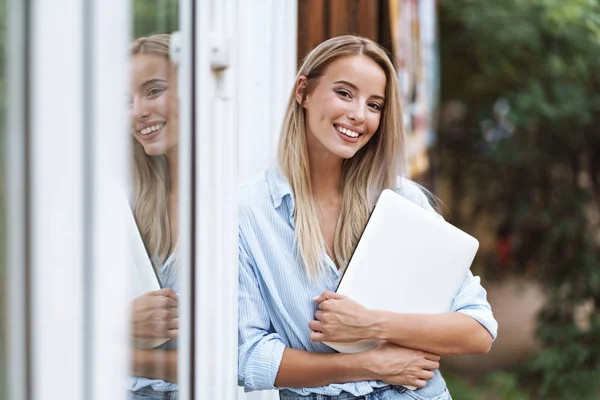 Hermosa chica sonriente sosteniendo ordenador portátil — Foto de Stock